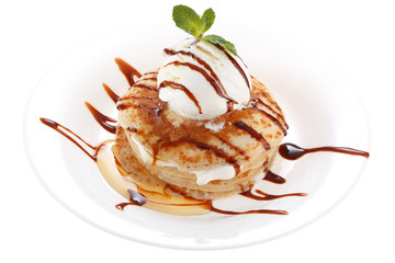 Serving pancakes with ice cream on the plate. Decorated with chocolate syrup and mint. Isolated on white background.