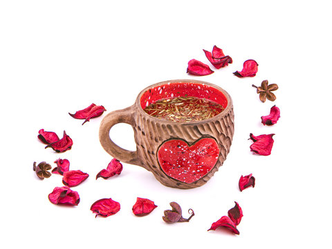 Valentine's Day still life. Clay cup with a red heart and rose petals on white background.