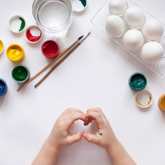 Children's hands paint Easter eggs. The child is drawing, step by step