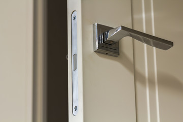 Naklejka premium Modern stainless steel door handle on white wooden doors