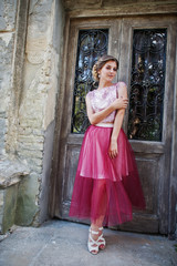 Portrait of a lonely young bridesmaid posing next to the old doors.