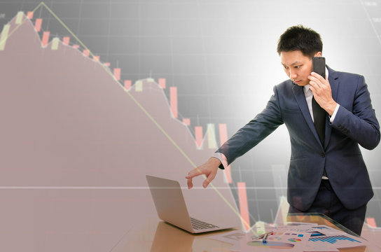 Double exposure of young businessman talking on the phone with stress and the technical chart of stock losses in background.