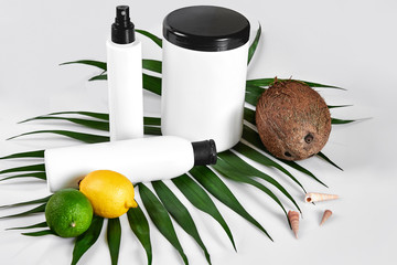 Natural cosmetics for home spa. Top view bottles of cream, shampoo, mask with essential oil, fresh lime fruit, green leaf decor, white background