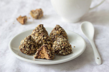 Homemade sweets with peanut butter, chocolate glaze and waffle crumbs on a table with a cup of tea, selective focus