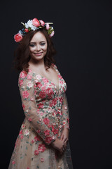 Fototapeta premium Beautiful young girl with flowers in her hair. Photo made in Studio on dark background.