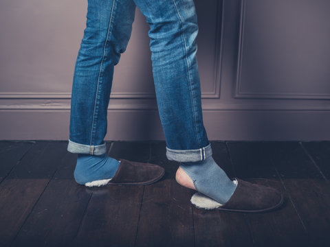 Young man with slippers on wooden floor