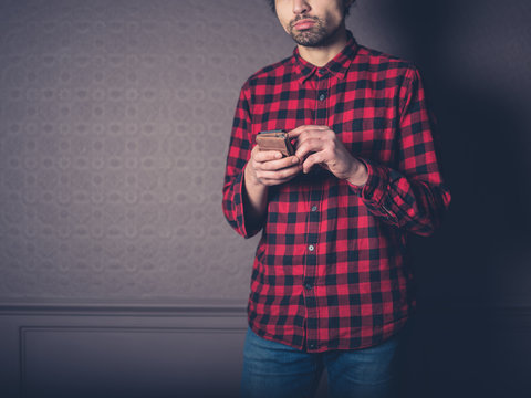 Young man in flannel shirt is using smart phone