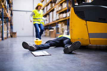 An injured worker after an accident in a warehouse. - obrazy, fototapety, plakaty