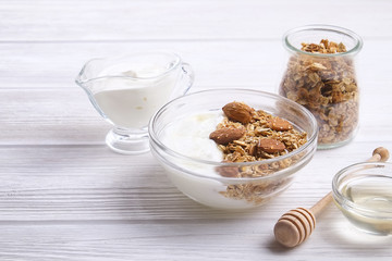 Glass bowl with Greek yogurt and mixed nuts. Healthy sports vegetarian protein rich diet, homemade granola breakfast with milk, honey, almond, cashew, hazelnut, rolled oats. Top front view, background