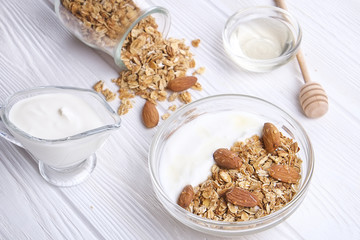 Glass bowl with Greek yogurt and mixed nuts. Healthy sports vegetarian protein rich diet, homemade granola breakfast with milk, honey, almond, cashew, hazelnut, rolled oats. Top front view, background