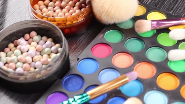 Make-up brushes laying on colorful cosmetic palette. Close up. 
