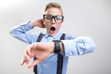 I am seriously late. Waist up portrait of astonished boy with wide opened mouth is checking the...