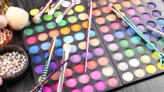 Make-up brushes laying on colorful cosmetic palette. Close up. 