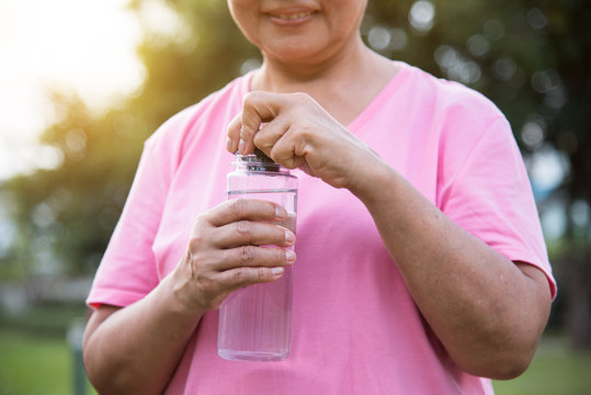 Asian senior Female holding bottle of water.