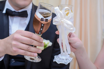 The bride and groom hold wedding glasses in hand closeup