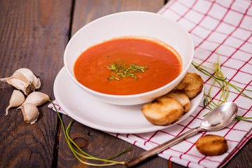 tomato soup  with pasta and chives and bread crouton in white plate on wood table 