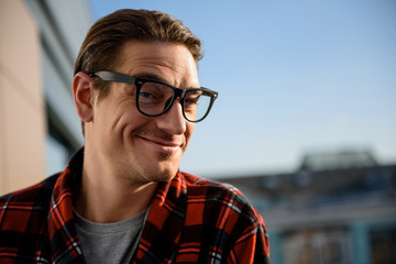 Happy adult man looking at camera with glad smile. He is standing on the balcony. Focus on his...
