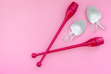 Equipment for rhythmic gymnastics. Clubs and gymnastics shoes on pink background top view on pink background top view copy space
