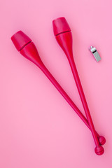 Equipment for rhythmic gymnastics. Clubs on pink background top view copy space