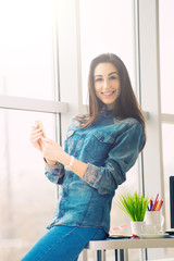 pretty designer looking woman with smartphone in office