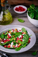 Fresh green salad with spinach, walnuts, feta cheese and pomegranate