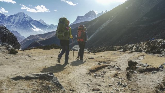 Two women with backpacks are walking along the path in Nepal mountains. Slow motion shot. 4K, UHD