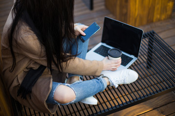 Happy woman with smartphone or laptop in city centre on wooden place