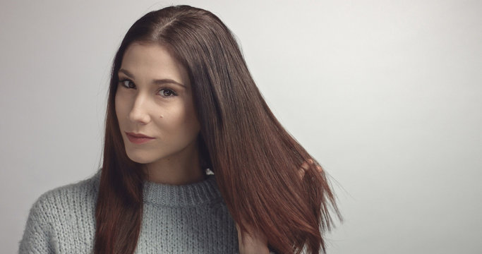 spanish woman sreaching and touching her straight dark hair. ideal skin portrait