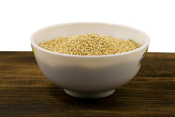 Raw quinoa in a white bowl on a wooden board