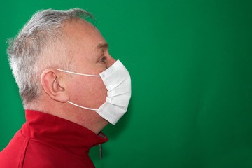 a grown man in a medical mask looking forward from left to right on a green background