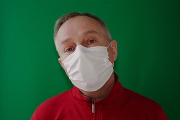 a grown man in a medical mask looking  forward on a green background