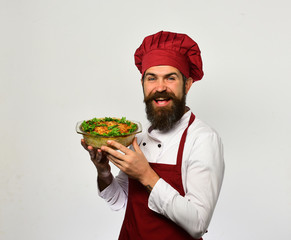 Cook with happy face in burgundy uniform holds baked dish