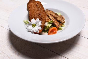 Meat steaks, salad and toast decorated with chamomile