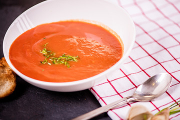 close up detail of tomato soup in white plate on white background 