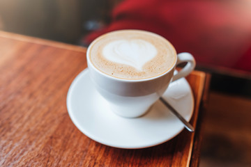 Hot coffee with milk in white mug on wooden table. Latte coffee art cup with heart shaped surface. Fresh invigorating drink. Having morning beverage. Coffee shop. Espresso for you