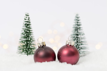 rote Christbaumkugeln mit Tannen im Schnee