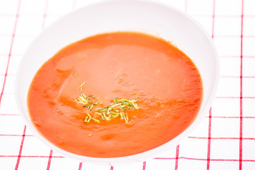 close up detail of tomato soup in white plate on white background 