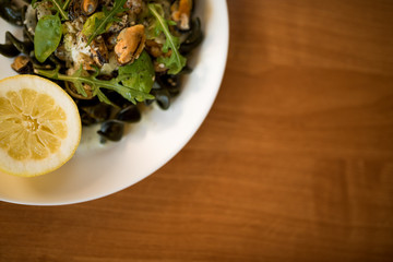 Black pasta with seafood in white cream sauce and lemon