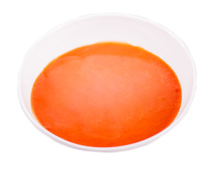 close up detail of tomato soup in white plate on white background 