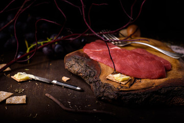 Raw ribeye beef steak, cooking ingredients on wooden table.