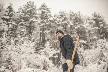 Bearded man with axe in snowy forest.