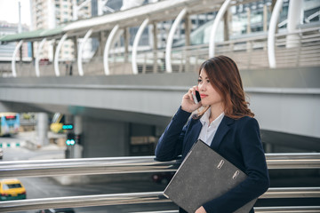Fototapeta premium Portraits of beautiful asian woman look confidence is standing and holding cellphone . she using smartphone calling to conversation with customer.