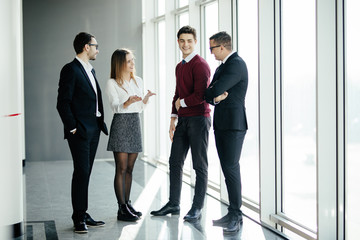 Full length of group of happy young business people walking the hall in office together
