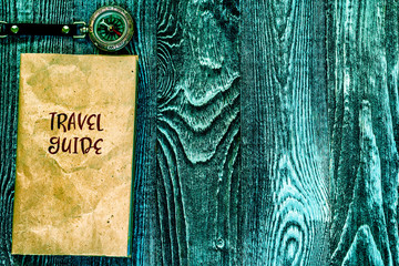 Travel guide and compass on wooden background