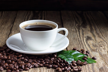 Cup of coffee with coffee beans on wooden background
