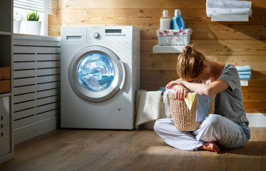 tired housewife woman in stress sleeps in laundry room with washing machine  .