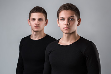 The two twin brother stand on the gray background