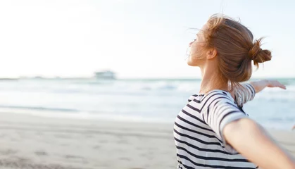 Fotobehang happy woman enjoying freedom with open hands on sea © JenkoAtaman