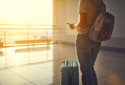 young woman waiting for flying at airport at window with suitcase  .