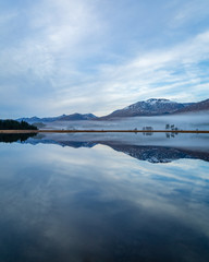 landscape view of scotland and loch tulla at blue hour in winter with calm waters and fog 